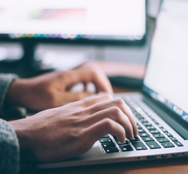 hands of a man on his laptop looking for an e-therapy course