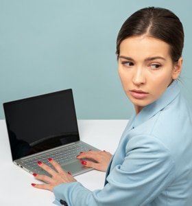Contracting for Online Therapy - woman in front of her laptop looks over her shoulder to ensure privacy