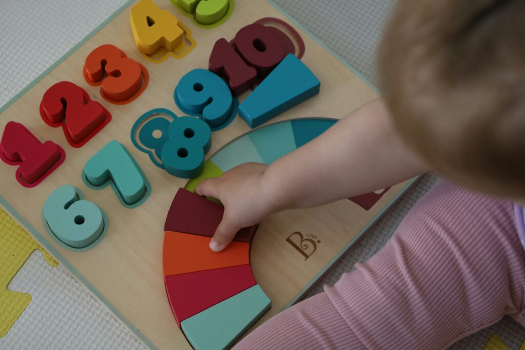 A young child organises coloured wooden blocks to match the pattern on a wooden board.